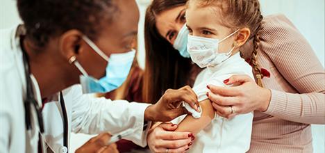 Doctor-vaccinating-child-wearing-mask Vacunas COVID para niños